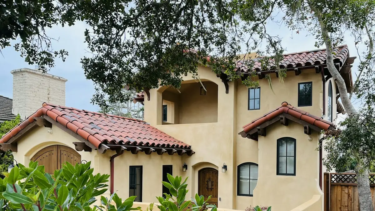 Two-story Mediterranean house with a red tile roof and arched windows - Water Heater Repair in Tustin